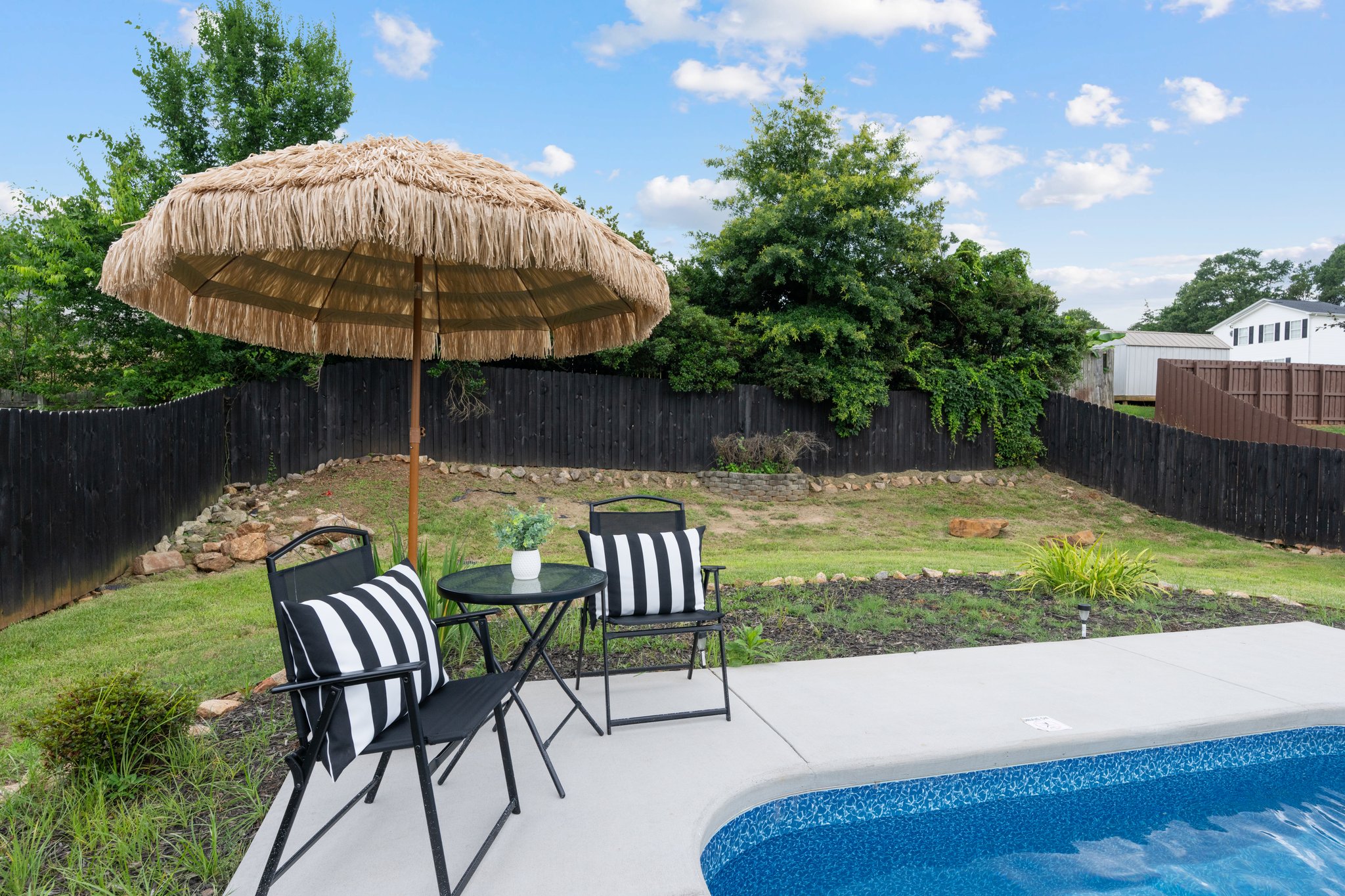 Charming patio seating area with thatched umbrella, striped chairs, and garden views at Greenville vacation retreat