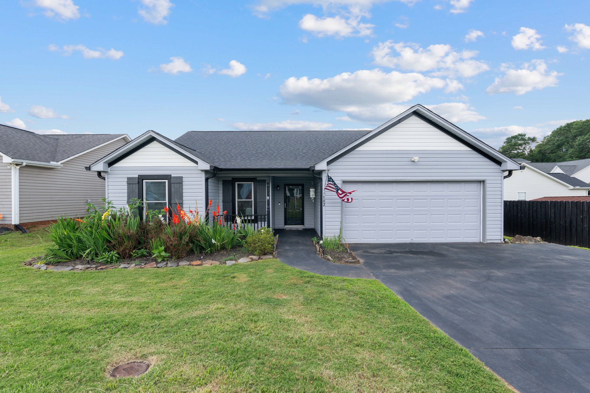 Modern two-car garage home with crisp white exterior, black shutters, and manicured landscaping in Greenville neighborhood