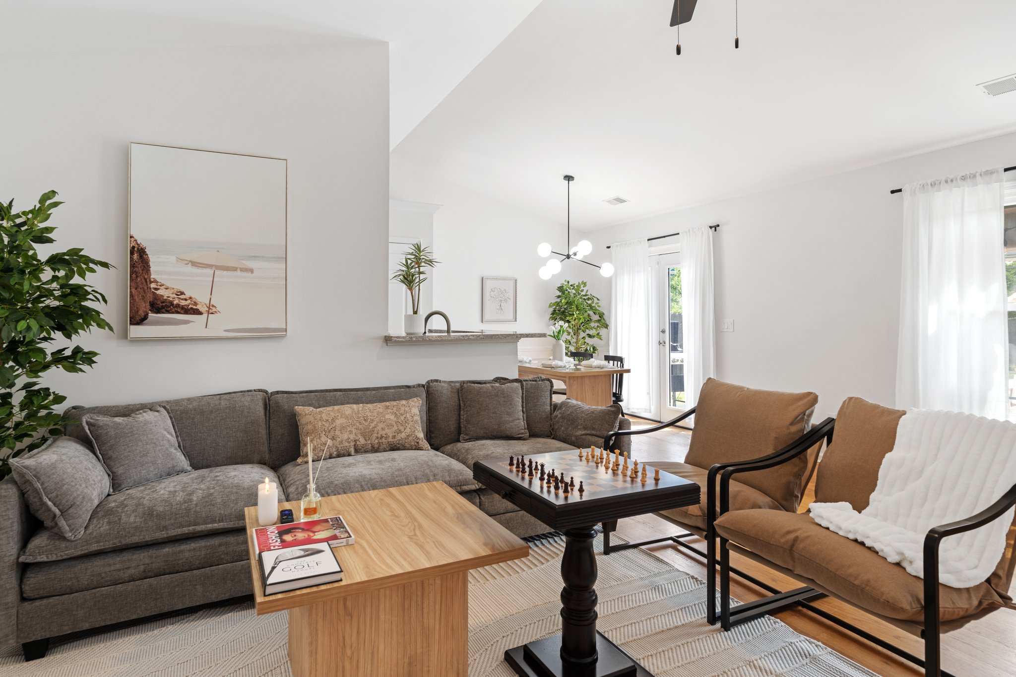 Contemporary dining and kitchen space with natural wood table, white cabinetry, and modern pendant lighting in Greenville