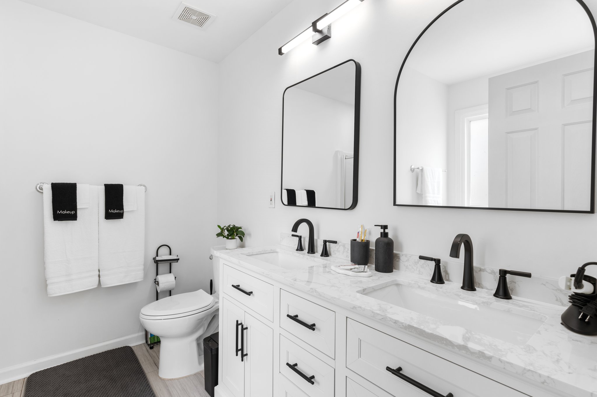 Luxurious master bathroom with dual marble vanity, black fixtures, and large mirrors at Greenville vacation home