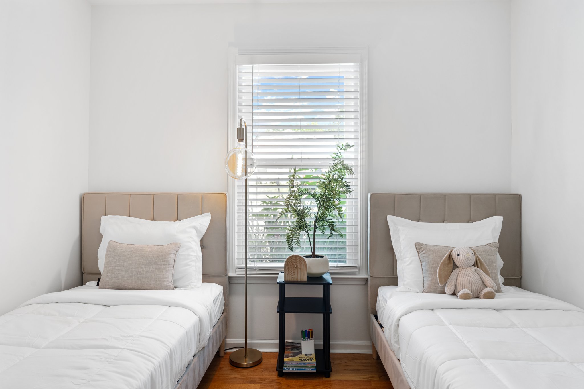 Bright children's bedroom with twin beds, white linens, and natural light from windows at Greenville family home