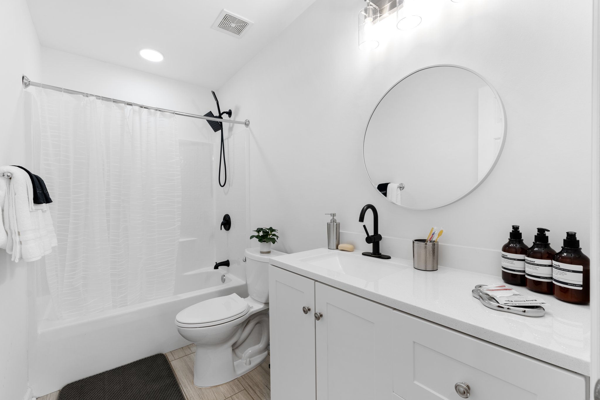 Clean and modern guest bathroom with white subway tile shower, pedestal sink, and spa-like amenities