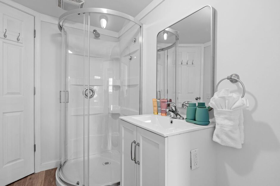 Comfortable guest bedroom with queen bed, white bedding, ceiling fan, and sliding glass doors to shared deck